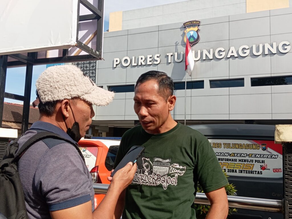 AGS (memakai koas warna hijau) warga Desa Junjung, Kec. Sumbergempol, Kab. Tulungagung saat di wawancarai awak media usai penuhi panggilan penyidik di Mapolres Tulungagung. 